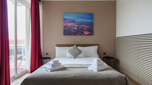 A hotel room with a bed, a cityscape painting, a view through the window, and a sliding door. - B&B Metropolitan (Naples)