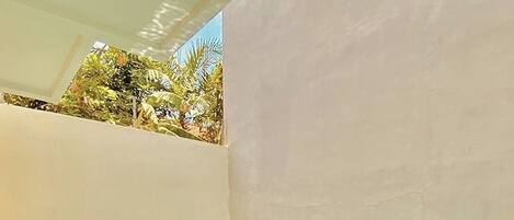 Una piscina rettangolare con acqua cristallina, circondata da un muro in pietra e un tetto piatto.