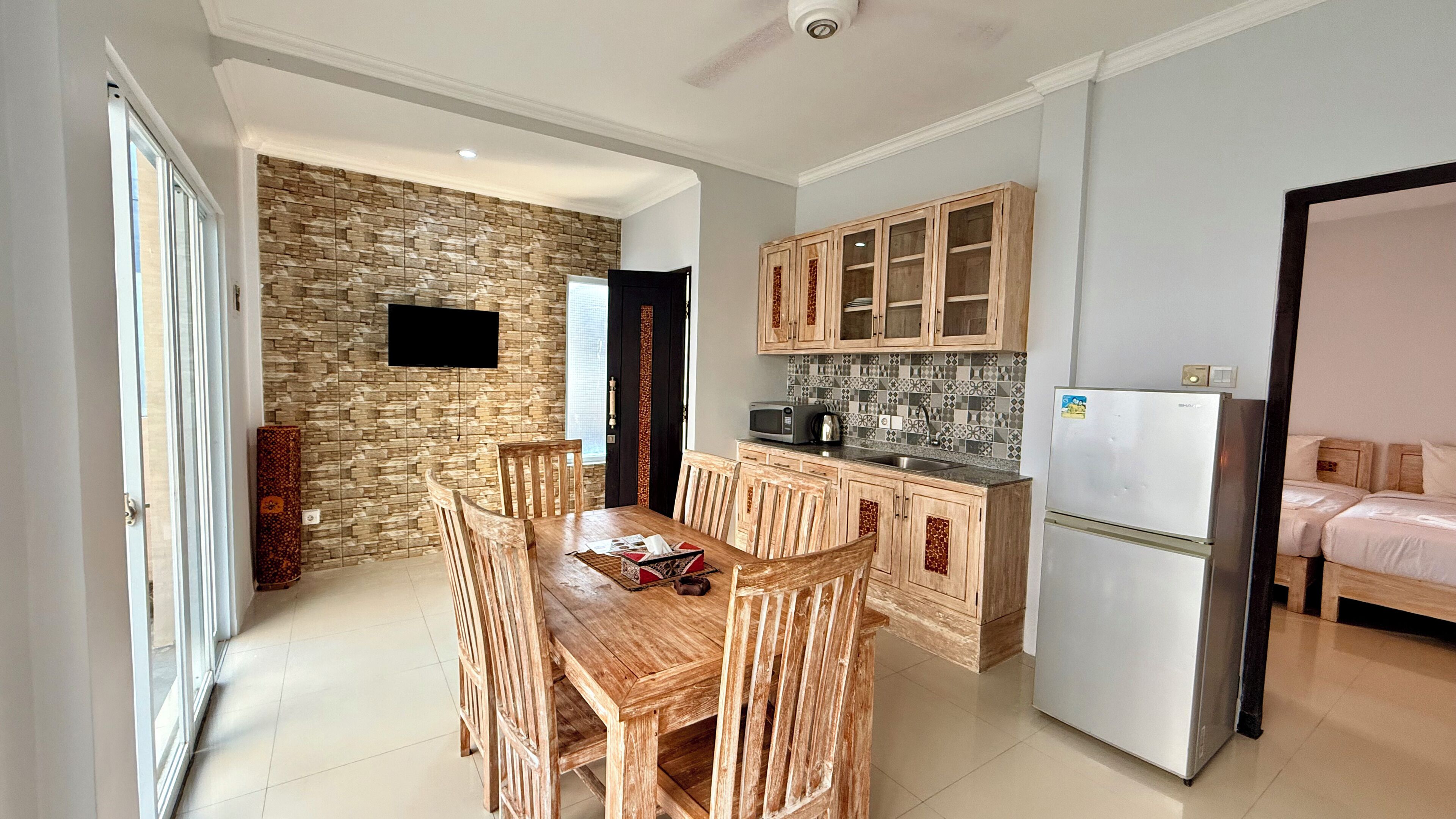A compact kitchen with wooden cabinets, a built-in microwave, and a refrigerator.