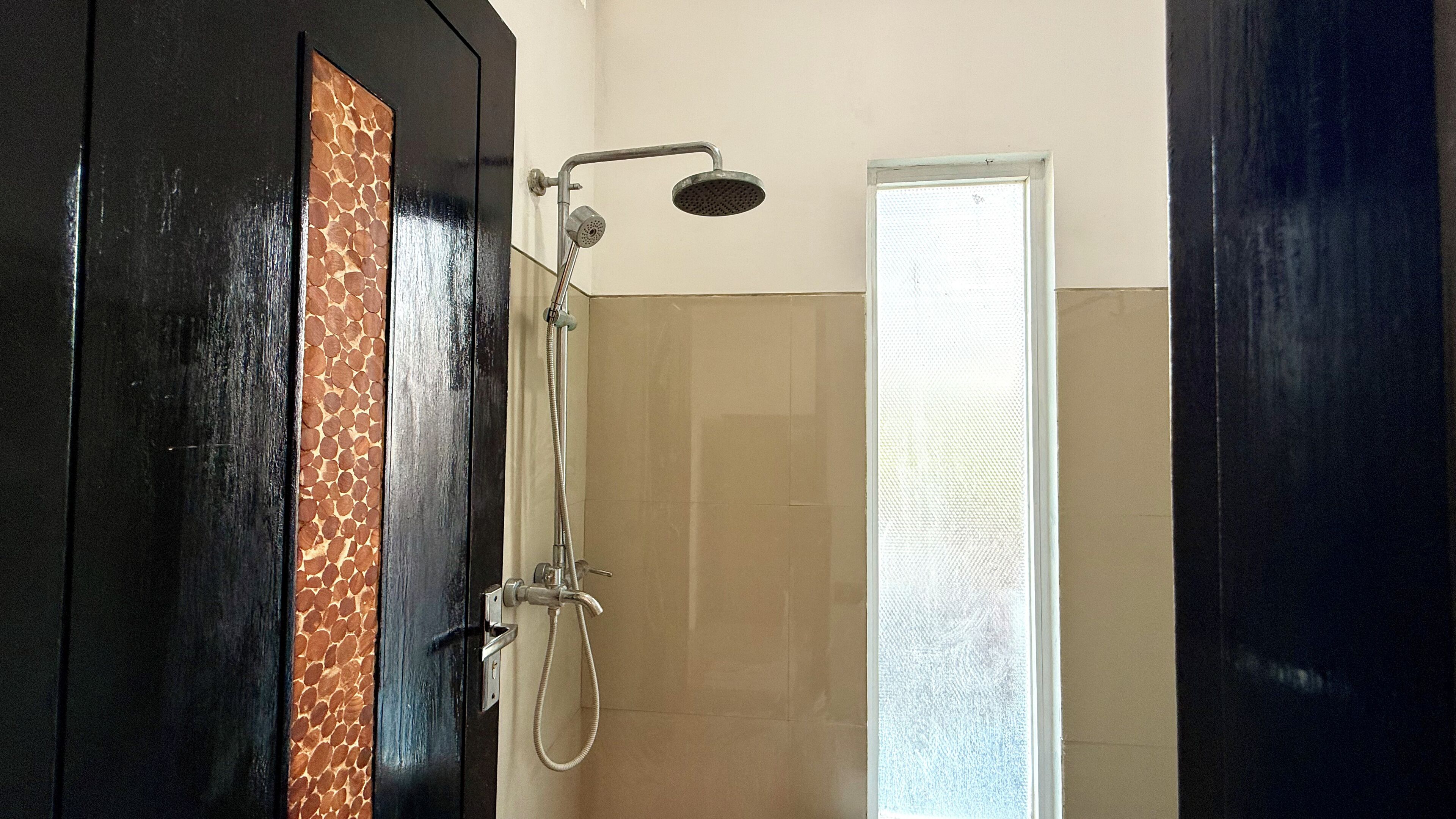 A shower area with a glass door, a showerhead, and a handheld shower attachment.