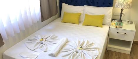Cama bem arrumada com toalhas e uma camisa branca dobrada sobre ela.