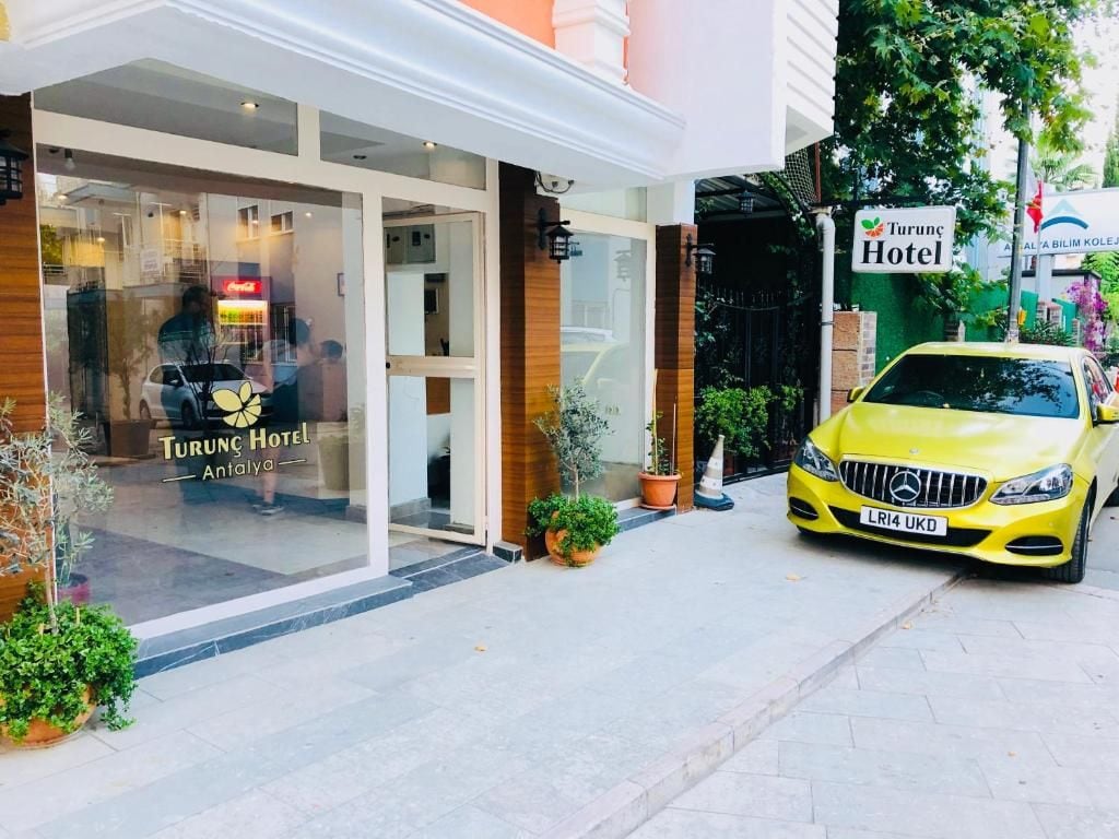 A hotel entrance with a yellow car parked outside.