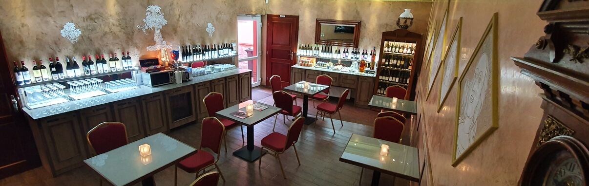Eine Bar mit mehreren Tischen und Stühlen, einer Weinauslage und einer Wanduhr.