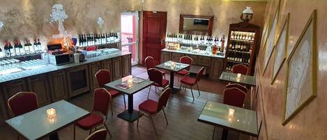 Eine Bar mit mehreren Tischen und Stühlen, einer Weinauslage und einer Wanduhr.