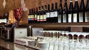 Zona de bar con botellas de vino, copas y una máquina de café.