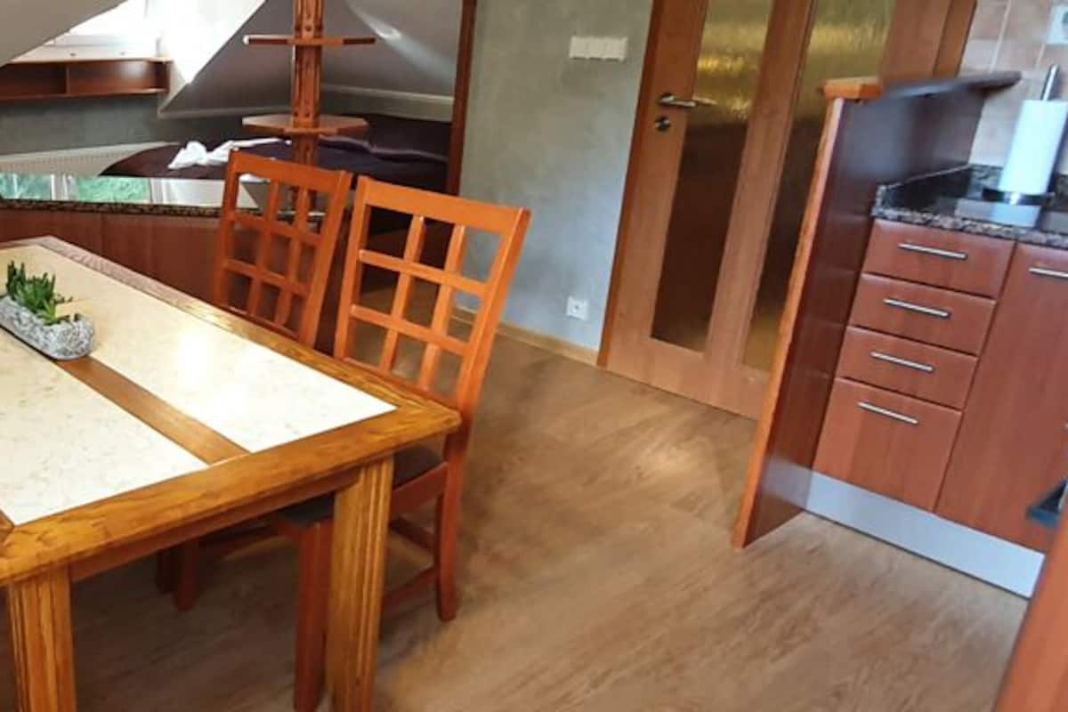 A compact kitchen with wooden cabinets, a dining table, and chairs.