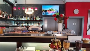 Una zona de bar con una variedad de botellas, vasos y alimentos.