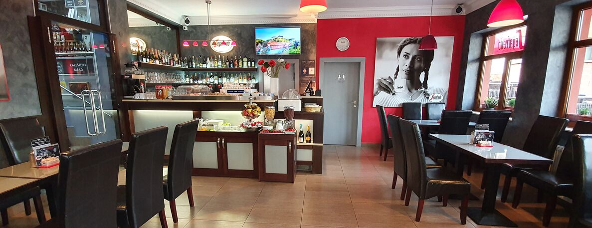 A restaurant with a bar area, multiple seating options, and a television screen.