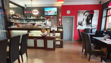 A restaurant with a bar area, multiple seating options, and a television screen.