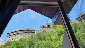 Vista de un edificio que recuerda a un castillo, con múltiples torres y una gran estructura central, rodeado de exuberantes árboles verdes.