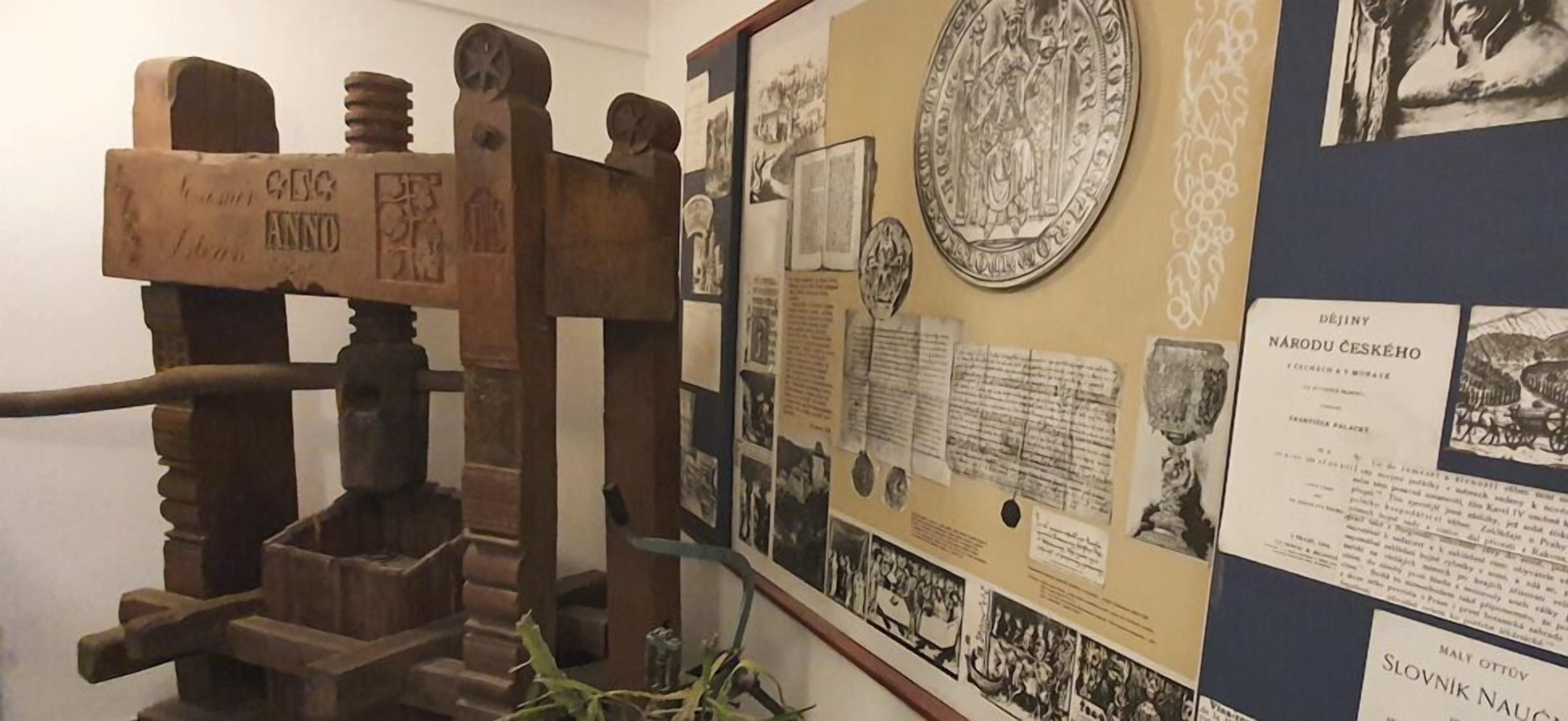 A historical exhibit with a wooden press, documents, and photographs.