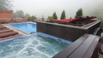 Un jacuzzi, una piscina con sillas de descanso y una zona de barbacoa.