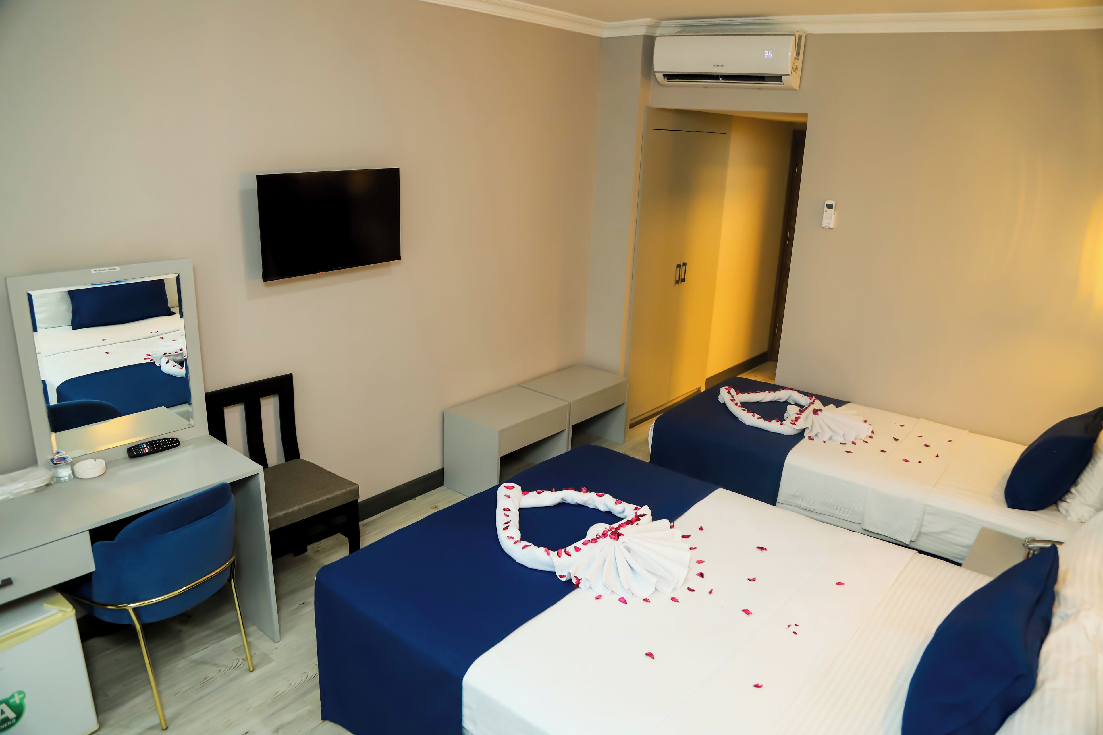 Habitación de hotel con dos camas, un escritorio, una silla, un televisor y un equipo de aire acondicionado.