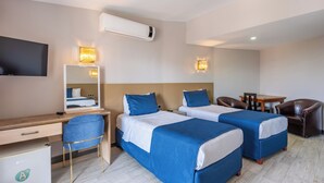 A hotel room with two beds, a desk, a chair, a TV, and a small table. - Safari Otel (Antalya)