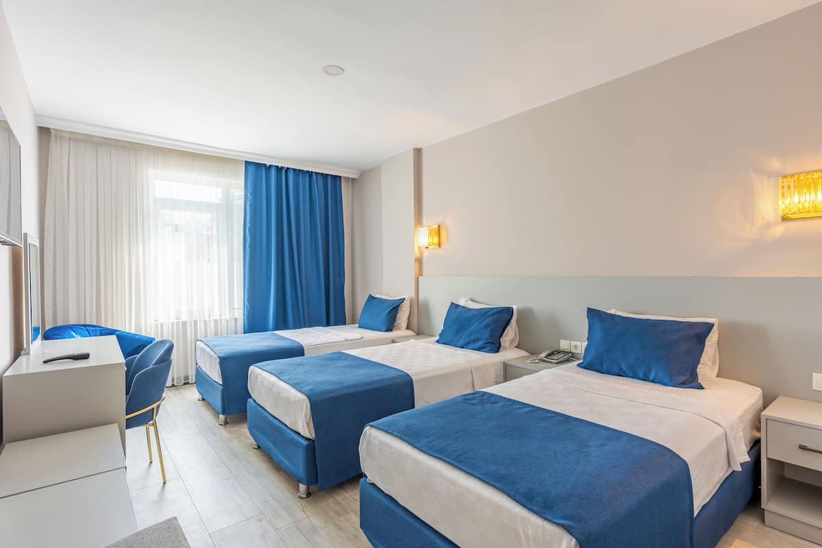 A hotel room with three beds, a desk, and a chair.