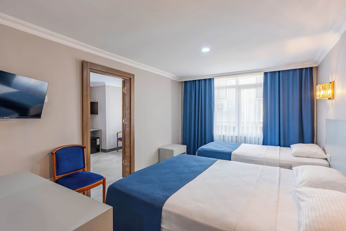 A hotel room with two beds, a desk, a chair, a TV, and a mirror.