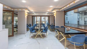 A modern conference room with glass tables and blue chairs, large windows, and a clean, white interior. - Safari Otel (Antalya)