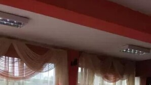 A living room with a sofa, a coffee table, a lamp, and a glass display case with shoes. - The Lions Den Hotel (Addis Ababa)