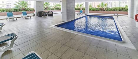 Zona de piscina con sillones reclinables y un extintor.