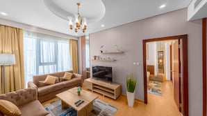 A modern living room with a sofa, TV, coffee table, and decorative plants.