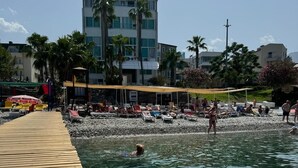 Une plage avec une promenade en bois menant à l’eau, une eau claire et des gens qui se baignent.