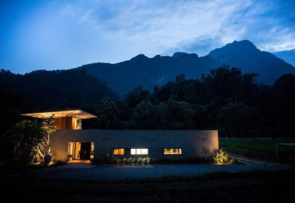 Una casa moderna con techo plano, ventanas amplias y una entrada bien iluminada.