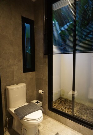 Un baño con inodoro, toalla y cabina de ducha de vidrio.