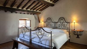 A bedroom with a wooden ceiling, a metal bed frame, a bedside table, and a lamp. - La Terrazza Cortonese (Cortona)