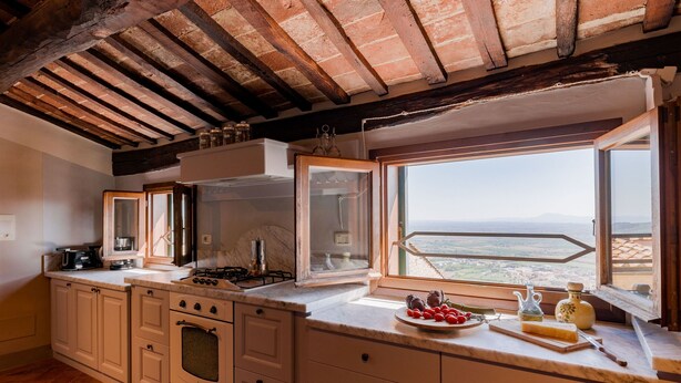 A kitchen with a large island, a stove, oven, and a window with a view. - La Terrazza Cortonese (Cortona)
