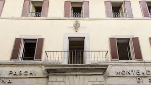 A building facade with a central entrance, two balconies with metal railings, and signage indicating "PASCHI" and "MONTE DI S". - La Terrazza Cortonese (Cortona)