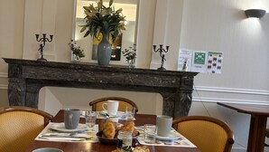 Une table à manger dressée avec des aliments pour le petit-déjeuner, notamment des croissants et du pain, et un vase rempli de fleurs.