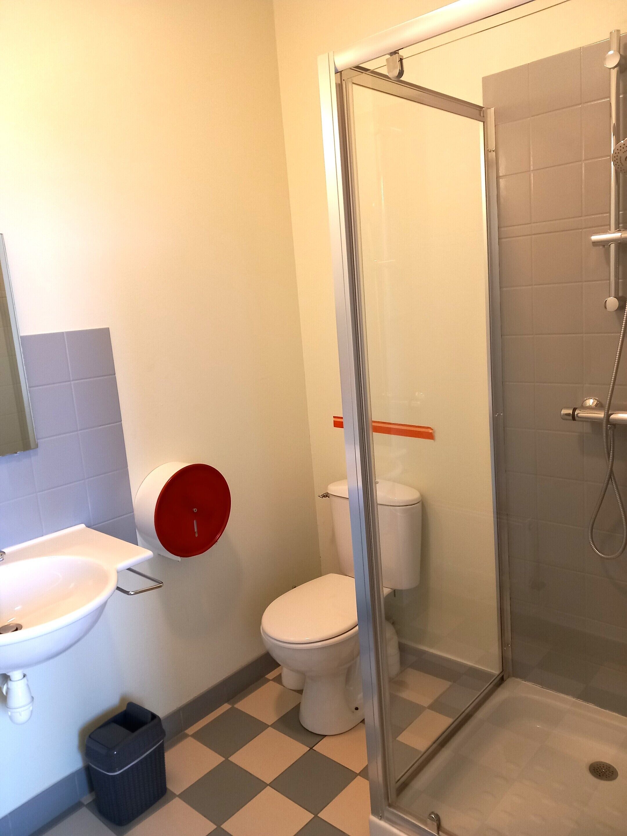 Et badeværelse med toilet, håndvask og bruser.