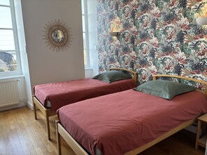 Una habitación con dos camas individuales, una lámpara de pared y una ventana con vistas.