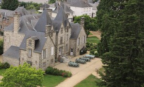 Un bâtiment en pierre doté de nombreuses cheminées et d’une cour pavée avec des espaces de repos en plein air.