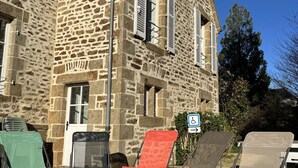 Un bâtiment en pierre doté d’une porte et de fenêtres, de chaises d’extérieur et d’un panneau indiquant qu’il est accessible aux personnes en fauteuil roulant.