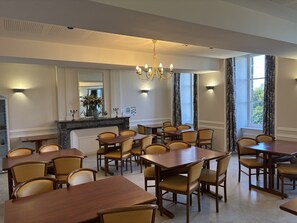 A dining area with multiple tables and chairs, a chandelier, and a mirror above a counter. - Château du Bourg (St Denis de Gastines)
