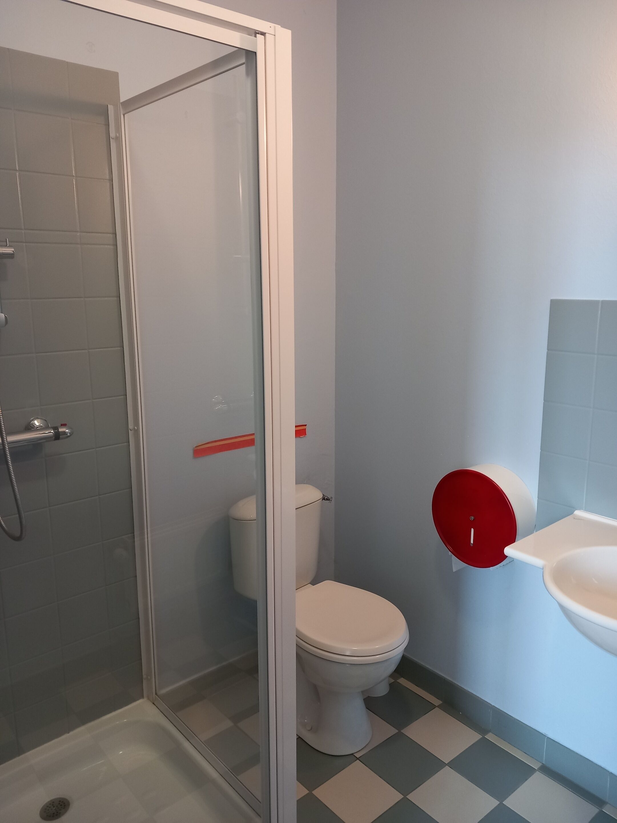 Une salle de bain avec douche, toilettes et lavabo.