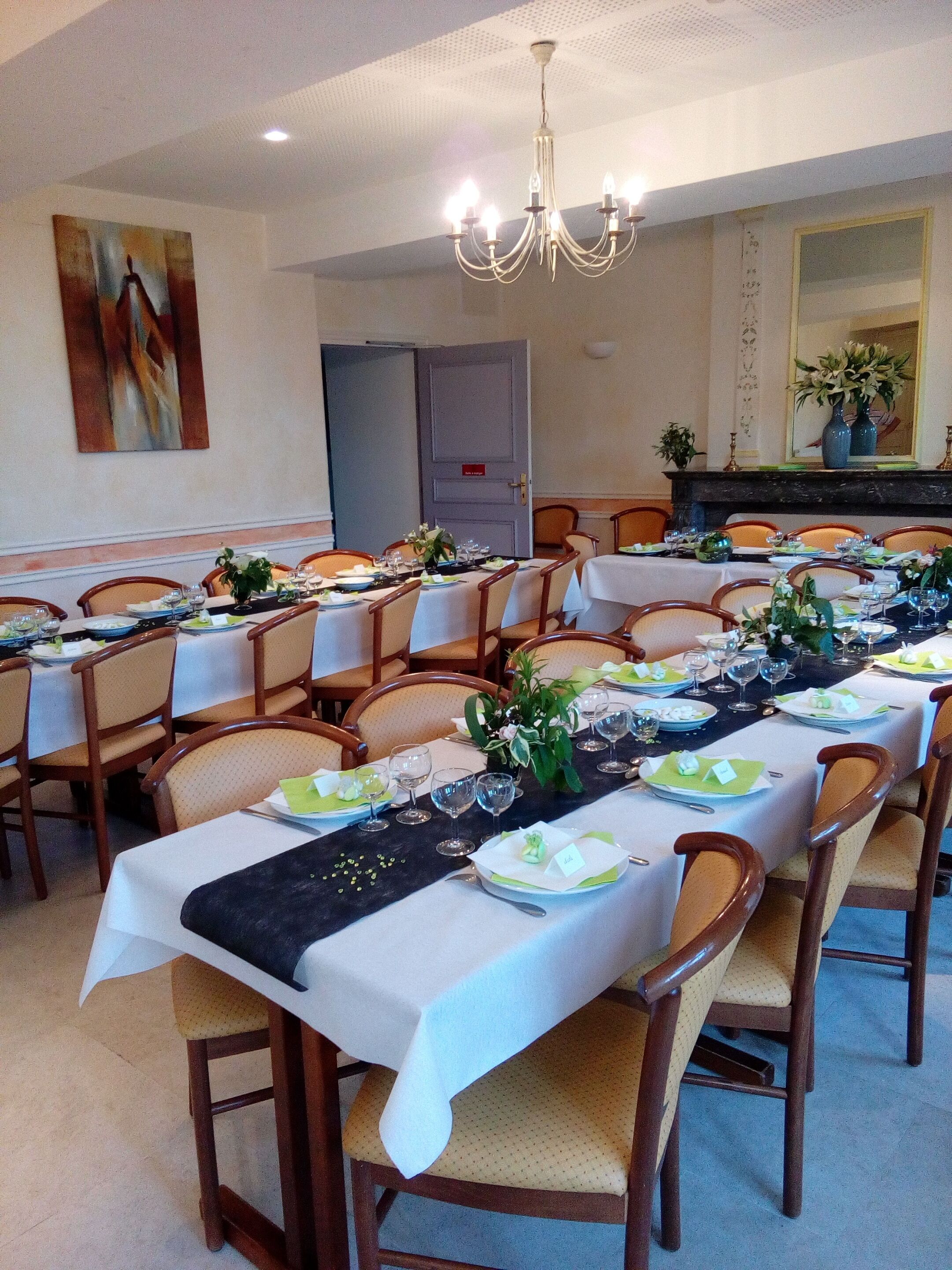 Un espace repas avec plusieurs tables dressées pour un repas, chacune étant agrémentée de chaises, d’assiettes et de verres.