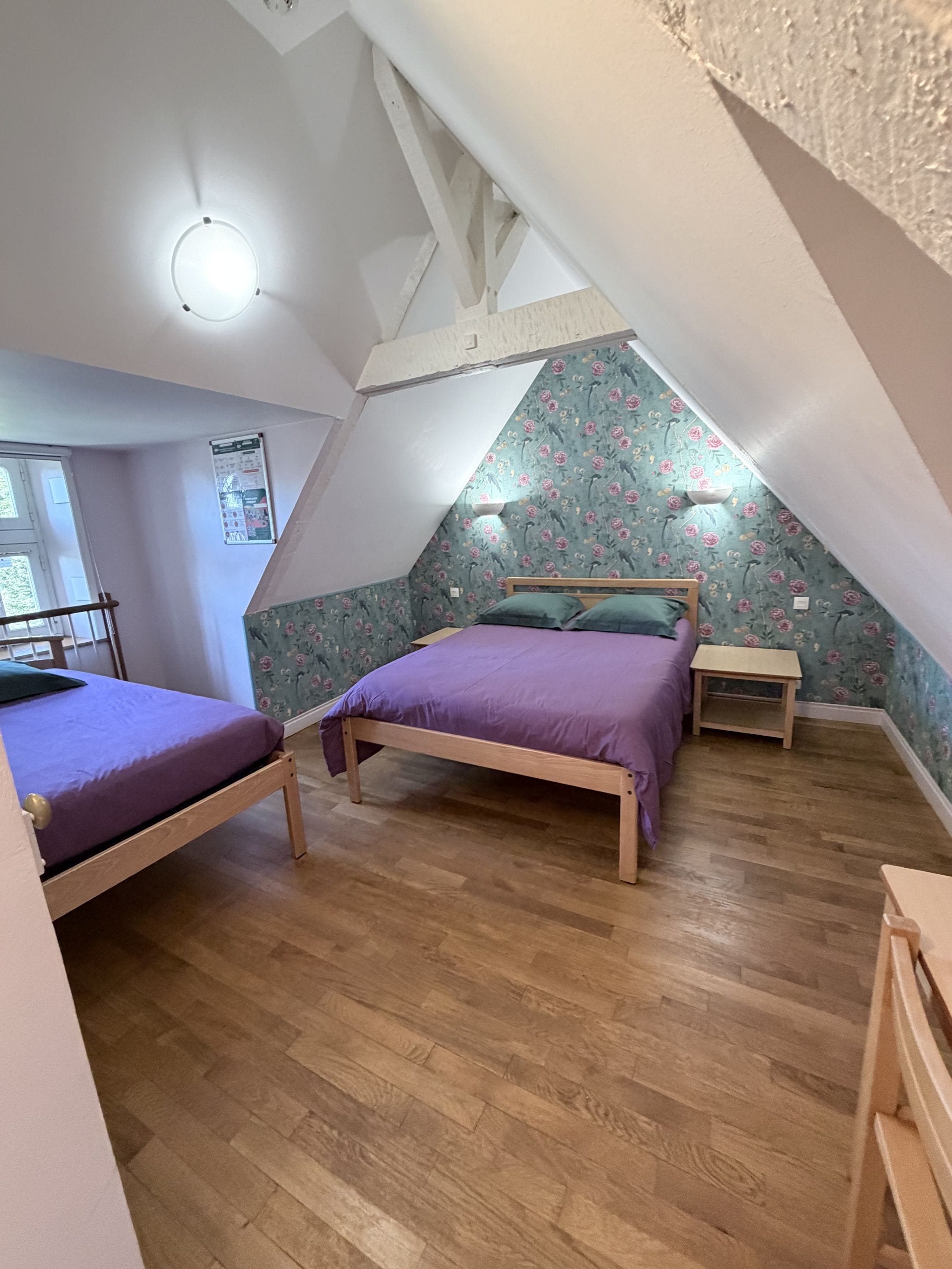 Een slaapkamer met twee bedden, houten vloeren en een schuin plafond.