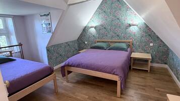 Een slaapkamer met twee bedden, houten vloeren en een schuin plafond.