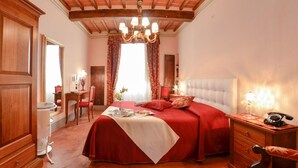 A bedroom with a large bed, a wooden desk, a chair, a dresser, and a chandelier. - Appartamento Il Teatro (Cortona)