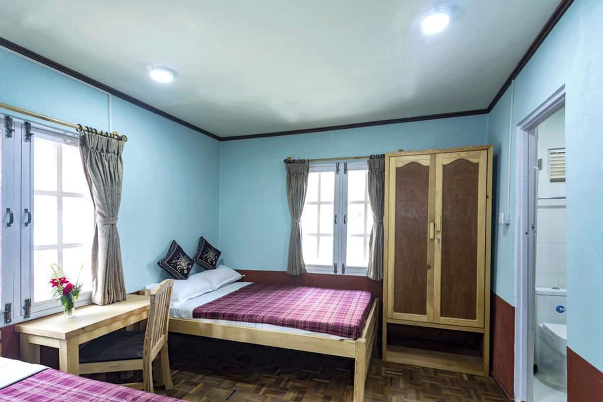 A bedroom with a bed, a desk, a wardrobe, and a window.