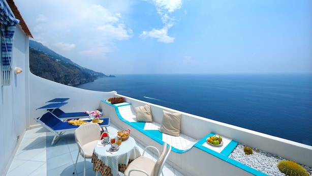 Un balcón con una mesa lista para el desayuno, con vistas a la costa.