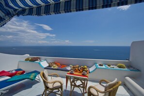 En terrasse med et bord dækket til morgenmad, med udsigt over havet.