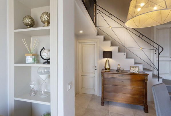 Un escalier au design moderne, une commode en bois et des objets décoratifs disposés sur des étagères.