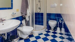 A bathroom with a white sink, a bidet, a shower enclosure, and a toilet. - Casa Emotion (Praiano)