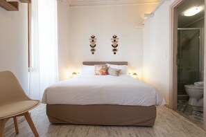 A bedroom with a large bed, a chair, and a bathroom visible through an open door. - Sofia Areopoli (East Mani)