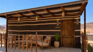 A King Suite with a striped exterior, a wooden door, a seating area with cushions, and a potted plant.