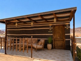 Una suite King con fachada a rayas, puerta de madera, zona de estar con cojines y una planta en maceta.
