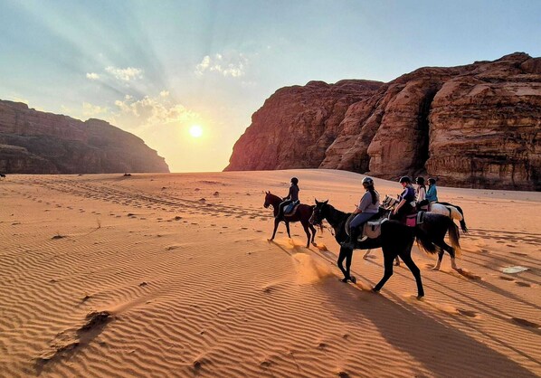A desert landscape with riders on horses. - Hasan Zawaideh Camp (Wadi Rum)